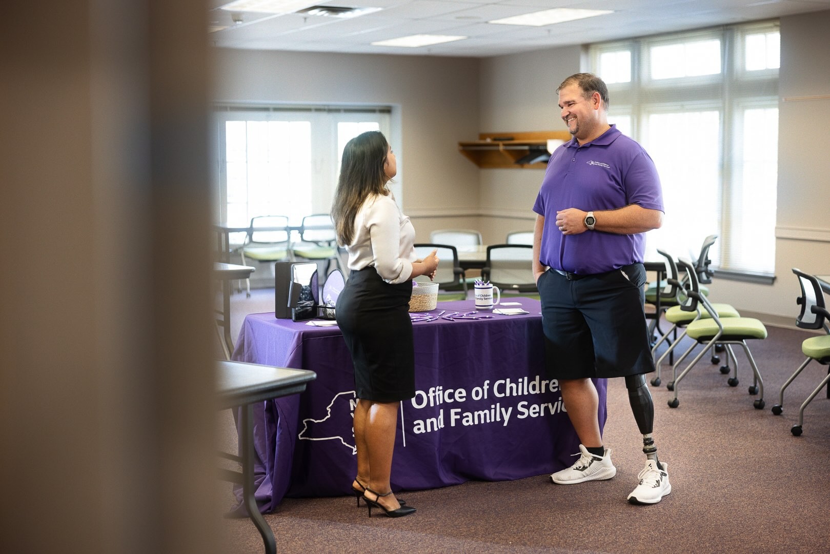 Man with prosthetic leg talking with a woman at a recruiting table.
